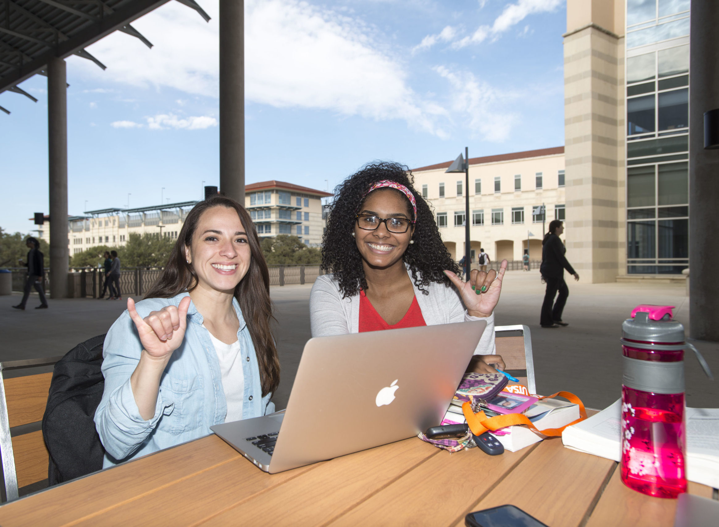 Two female UTSA students giving the birds up and smiling